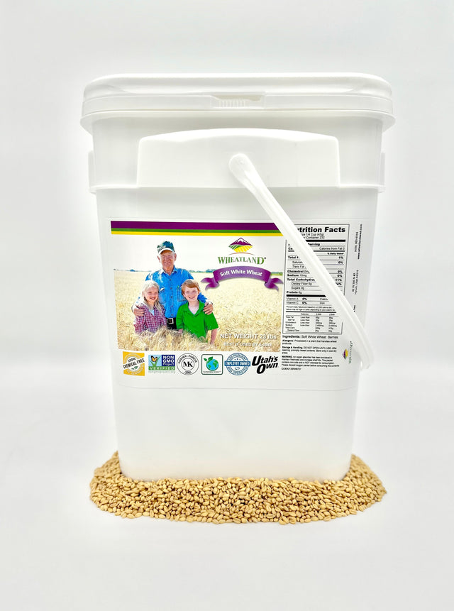 A white plastic bucket labeled with the product name and an image of wheat berries, indicating that it contains 23 lb of soft white wheat berries which are non-GMO, kosher, chemical-free, and have a 25-year shelf-life.